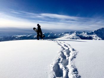 Man on snowboarding on snow covered mountain against sky