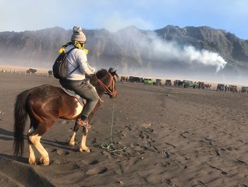 Man riding horse on field against sky