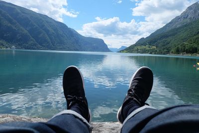 Low section of person by lake against mountains