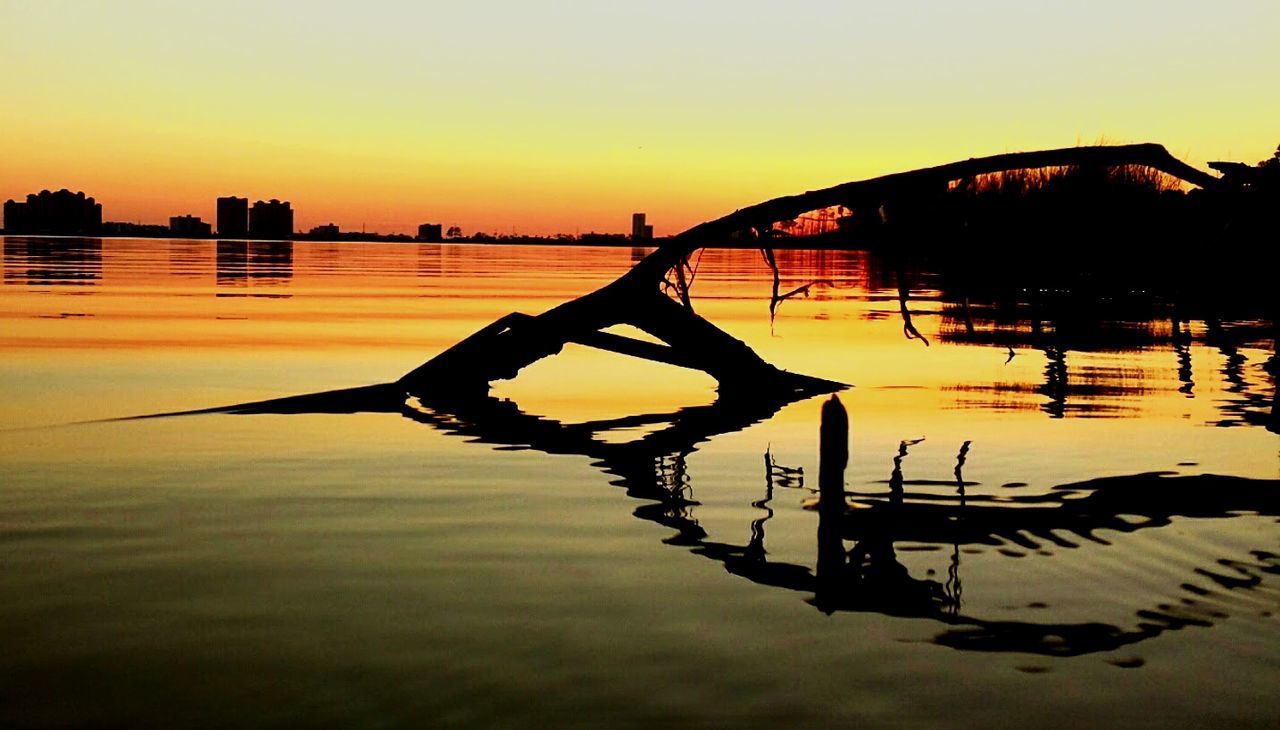 SILHOUETTE MAN ON BOAT AGAINST LAKE AT SUNSET