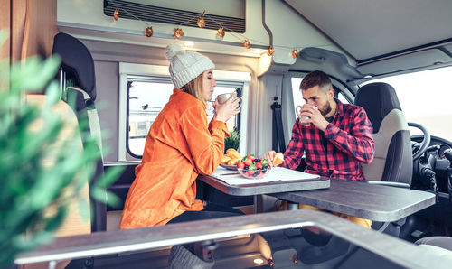 Couple drinking coffee while sitting in camper van