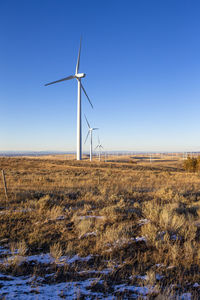 Wind turbines in field against blue sky