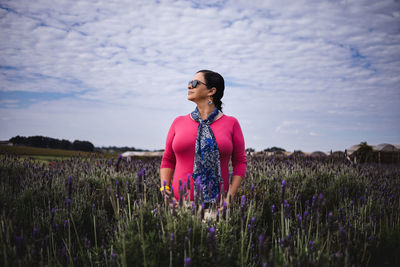 Young woman standing on field against sky