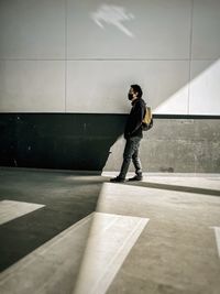 Side view of young man standing against wall