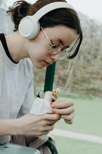 A teenage girl eats a sandwich in a train carriage.