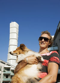 Man carrying dog, turning torso building in background