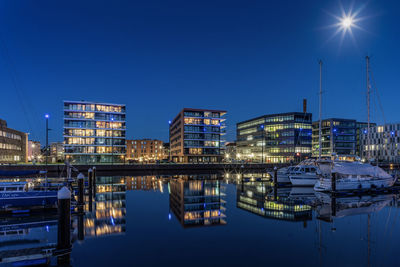 Sailboats moored in harbor against clear blue sky at night