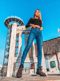 Low angle portrait of woman against blue sky