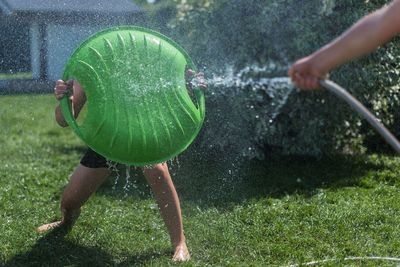 Children play outside with water and with a green shield. beautiful sunny day at the green garden.