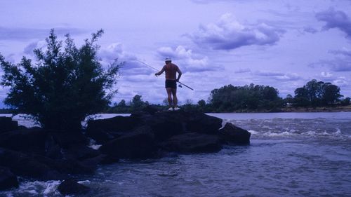 Full length of man standing on rock against sky