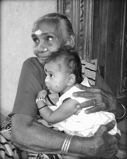 Portrait of grandmother and granddaughter embracing at home