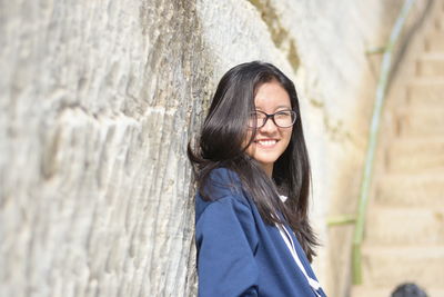 Portrait of smiling young woman against wall
