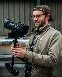 Young man holding camera outdoors