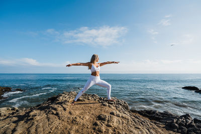 Young woman doing yoga exercises on the rocky beach