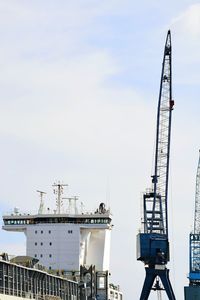 Cranes at commercial dock against sky