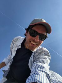 Low angle portrait of man wearing sunglasses against sky