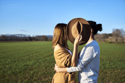 Rear view of women standing on field against sky