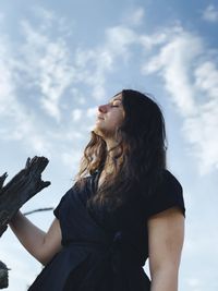 Low angle view of woman looking away against sky