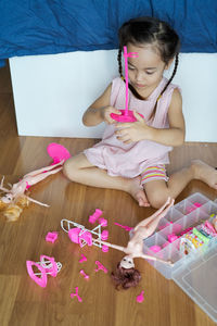 Cute girl playing with doll while sitting on floor at home