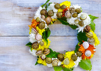 High angle view of homemade flower wreath with empty snail shell on table for decoration