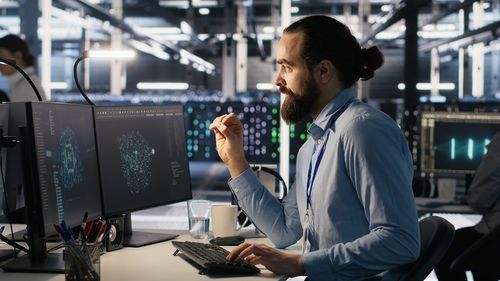 Side view of man using mobile phone while standing in office