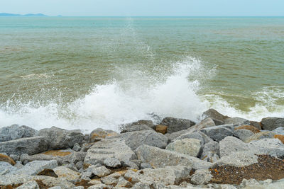 Scenic view of rocks on shore against sky