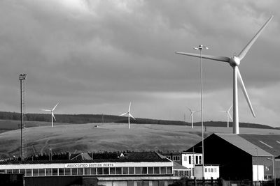 Wind turbines on field against sky