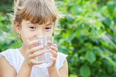 Portrait of young woman drinking water in park