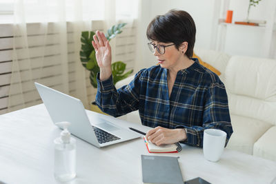 Side view of young woman using digital tablet while sitting at home