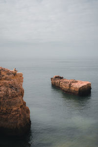 Rock on sea against sky