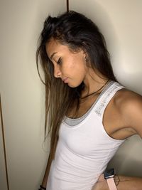 Beautiful young woman standing against wall at home