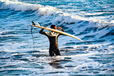 Rear view of man with arms outstretched on sea