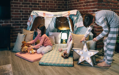 Male teenager helping little sister prepare a diy tent for pajama party