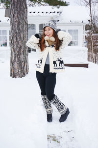 Portrait of smiling young woman standing in snow