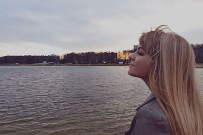 Woman with eyes closed in sea against sky