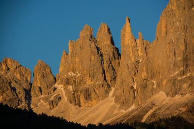 Panoramic view of rocky mountains against clear blue sky