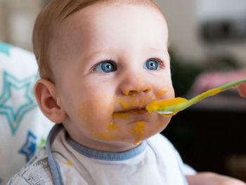 Close-up of cute baby boy eating food at home