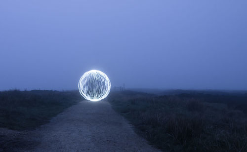 Illuminated light painting on landscape against clear sky