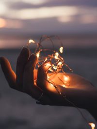 Cropped hand holding illuminated string lights