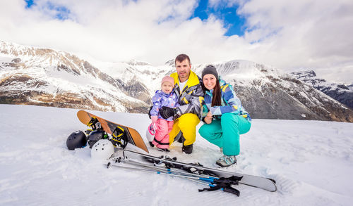 Portrait of family crouching on snowcapped mountain during winter