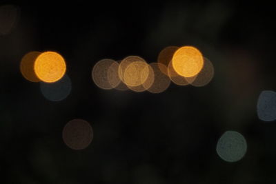 Defocused image of illuminated lights against sky at night