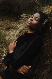 Young woman looking away while sitting on field