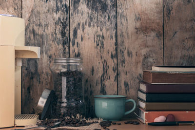 Close-up of roasted coffee beans in jar by books on table