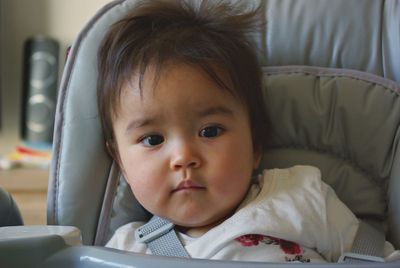 Close-up portrait of cute girl sitting on sofa