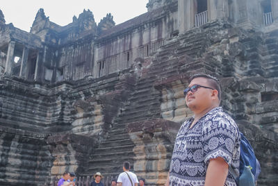 Low angle view of people standing by historic building