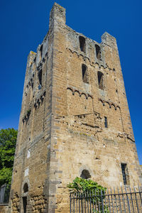 Low angle view of old ruins against clear blue sky