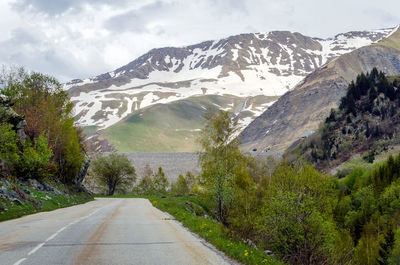 Road amidst trees and mountains against sky