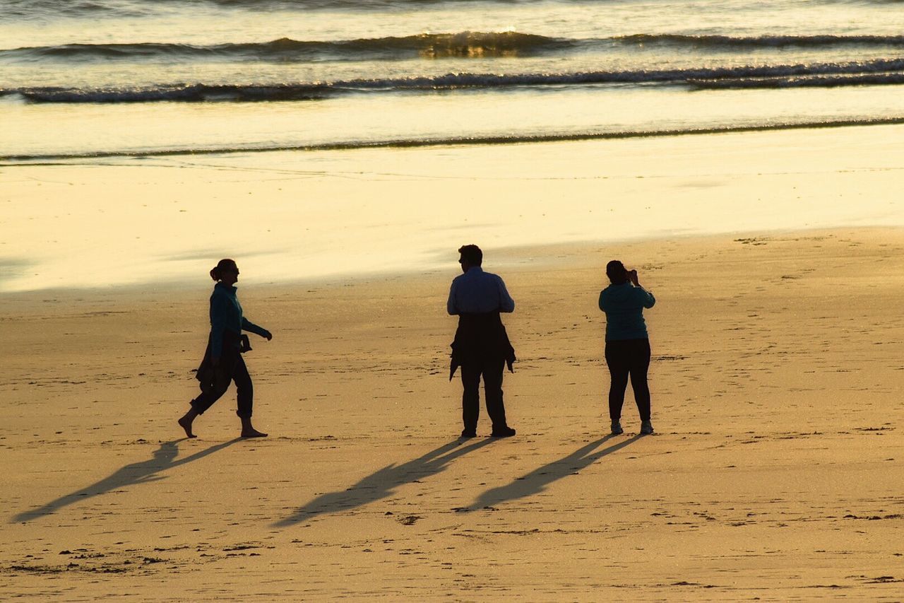 PEOPLE WALKING ON SANDY BEACH