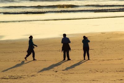 People walking on beach during sunset