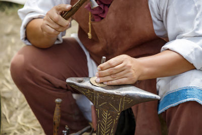 Close up image of the artist at work. he is carefully using a hammer made a decoration